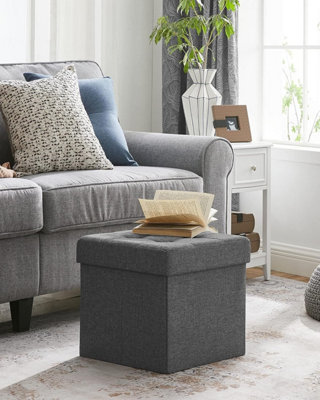 https://media.diy.com/is/image/KingfisherDigital/folding-storage-chest-ottoman-footstool-portable-picnic-seat-versatile-space-saving-cubes-max-load-300-kg-linenette-dark-grey~6955880325795_01c_MP?$MOB_PREV$&$width=618&$height=618