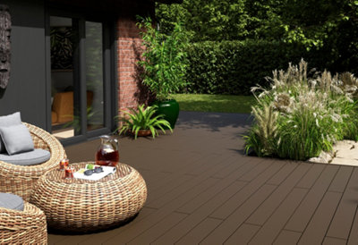 Modern garden with dark brown decking, wicker furniture, and a mix of materials, offering a relaxed and luxurious outdoor space.