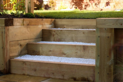 Beautifully crafted garden steps made of wood with white gravel treads, adding style, dimension, and practicality.