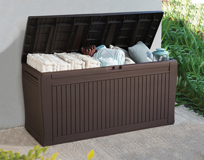 A plastic garden storage box with the top open to show garden cushions and blankets inside.