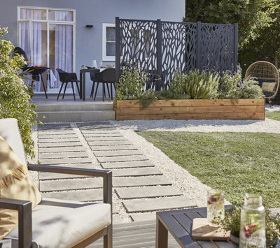 A garden with different zones; a cosy corner with an egg chair, a decking area with a outdoor coffee set and a raised patio with an outdoor dining set.