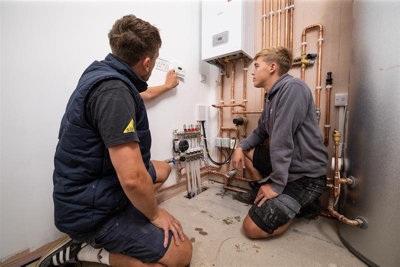 Tradespeople working on pipework for a boiler