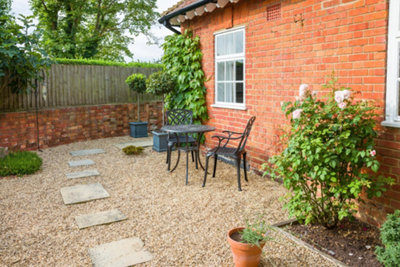 Low-maintenance gravel garden with a square slab stepping stone path.