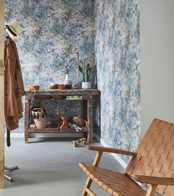 Green and blue abstract print wallpaper in a hallway with grey concrete effect flooring.