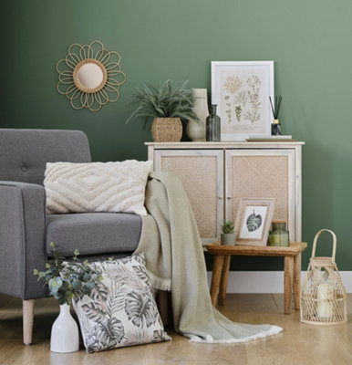 A green living room with a grey armchair and selection of home accessories.
