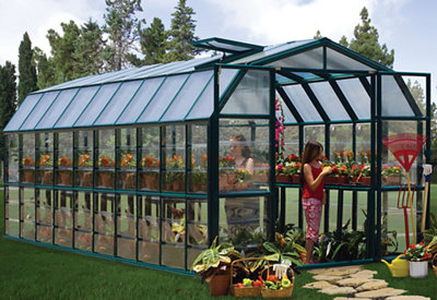A large rectangular greenhouse with a green metal frame and double doors at the front.