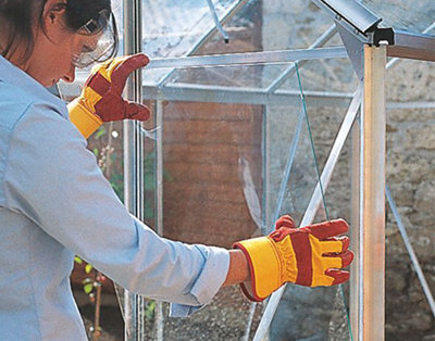Person wearing gloves placing a pane of glass into a greenhouse.
