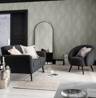 A grey living room with sage green leaf print wallpaper, a dark grey sofa and matching armchair.