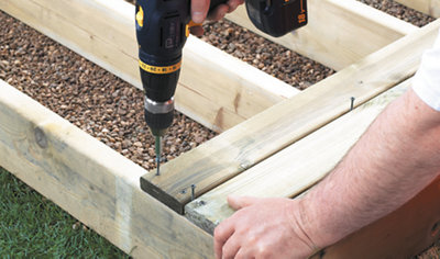 Person using a drill to drive a decking screw through a decking board to secure it to the decking joist below.