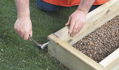 Using a socket wrench to tighten the screws joining two timber deck boards together in a corner.