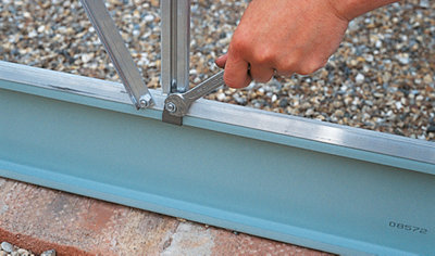 Using a spanner to tighten a nut that secures a greenhouse frame to the base.