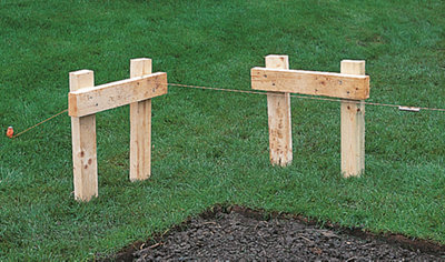 Two timber profiles positioned next to each other in the corner where decking will be laid, with a builder's line running between them to guide the layout.