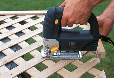 Using a jigsaw to cut a timber lattice panel in half while it is securely placed on a workbench.