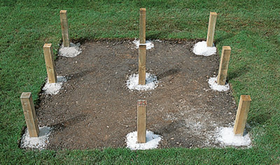 Nine deck joist support posts set in concrete, arranged in a square pattern, ready for the deck framework to be installed.