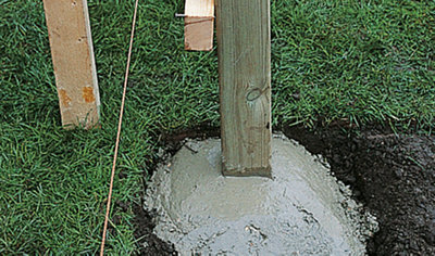 A deck joist support post set in quick-drying concrete, supported by a timber prop to keep it in place while it cures.