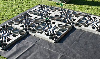 Interlocking plastic grids arranged on top of a weed membrane, creating a base for a garden shed.
