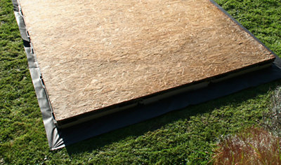 A wooden shed floor positioned on top of a plastic shed base, ready for the construction of the shed.