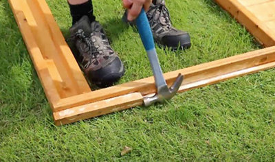 Using a hammer to tap the travel blocks out of the frame of a wooden playhouse.