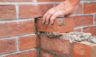 Laying a brick on a bed of mortar, on top of a wall that has been laid up to the level of the cavity. The brick is laid into the cavity.