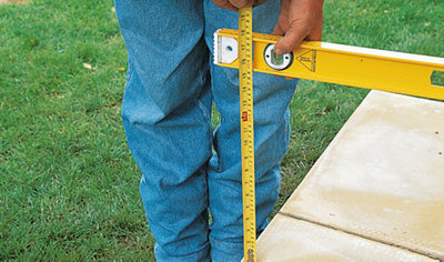 Holding a tape measure against a spirit level, which is held level.