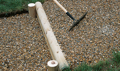 Using a rake to spread gravel above and below a log step.