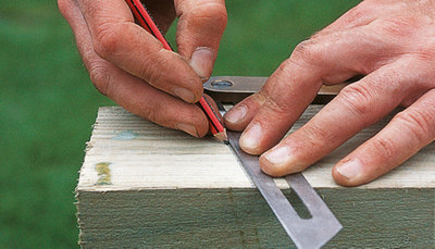 Person using a pencil and sliding bevel to mark a 20-degree angle at the top of a gate post.