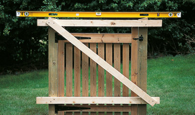 A spirit level resting across two gate posts with a gate in between, used to check that the gate posts are level.