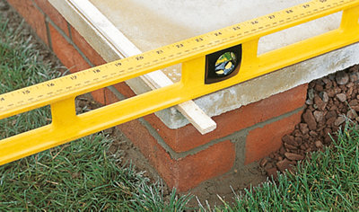 A spirit level resting on top of a 10mm thick piece of wood at the front of the step to check that the step has the correct fall.