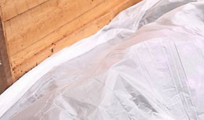 A plastic dust sheet laid on the ground, protecting plants next to a garden shed.