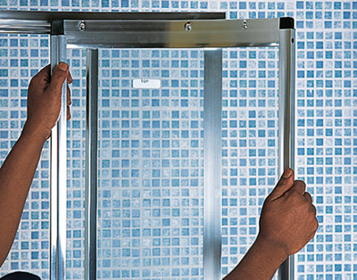 Person lining up a shower enclosure door to rails on a shower enclosure frame.