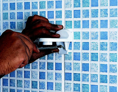 Person using a screwdriver to secure the bracket for a shower slider rail to a bathroom wall.