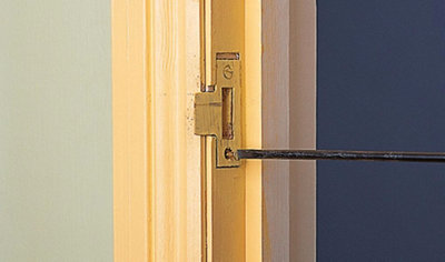Using a screwdriver to tighten screws and secure an internal door striker plate in place.