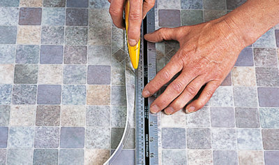 Running a utility knife along a metal ruler to cut the excess from a vinyl sheet to line up the patterns.