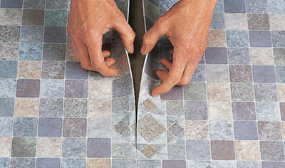 Lining up two pieces of sheet vinyl along a join ready to be glued down.