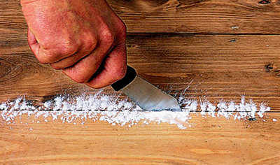 Person using a decorators knife to work talcum powder into the joint between two floorboards.