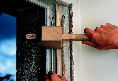 Using a mallet to tap the parting beads of a sash window into the sash window frame.