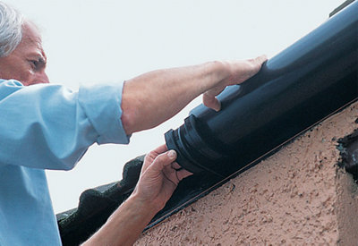 Person clipping a section of guttering into a bracket mounted on a fascia board.