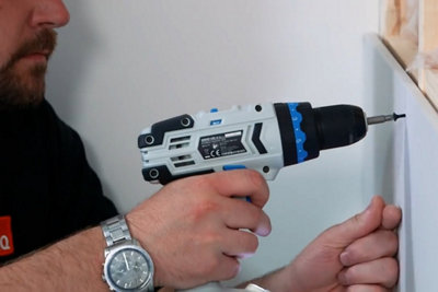 Using a drill to drive a plasterboard screw into a sheet of plasterboard to secure it to timber.