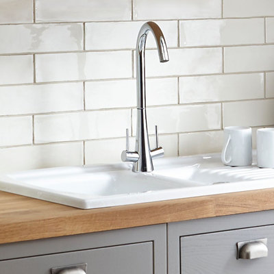 A chrome monobloc kitchen tap with two levers on either side of the tap body and a long spout with a curve at the top.