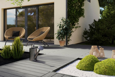 Large garden divided into distinct zones with a grey deck pathway, white gravel and lush shrubs.