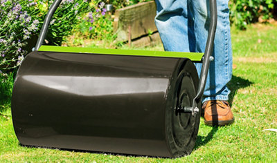A large lawn roller being pushed across a lawn.