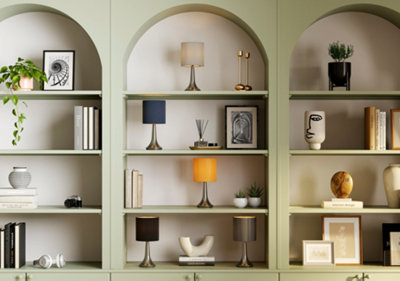 Light green built in shelving in a living room, full of books, framed art and stylish accessories.