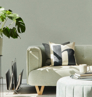 A light green living room with fabric textured wallpaper and a green fabric sofa.