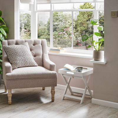 A light grey upholstered armchair in a living room bay window.