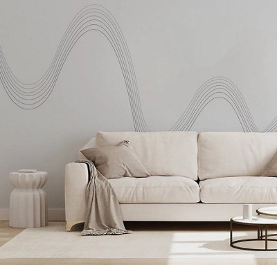 A white living room with a white sofa and rug, and a white wall mural with thin horizontal black wavy lines.