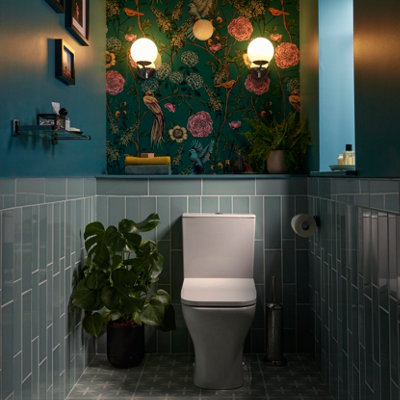 Maximalist cloakroom with blue half‑height tiles and floral wallpaper above.