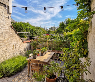 Mediterranean-style garden with terracotta pots, rustic wooden furniture and colourful tiles.