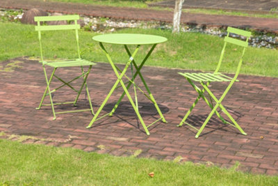 Green two-seater metal bistro set on a brick patio.