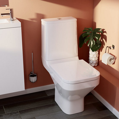 Modern close coupled toilet in an orange bathroom.