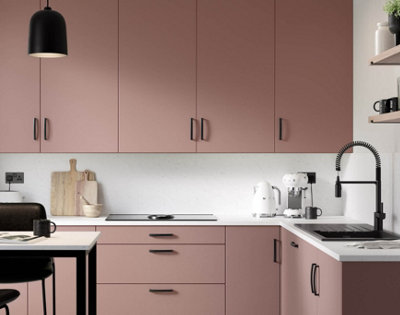 Modern pink ad white kitchen with black cabinet handles, lighting, sink, and tap.